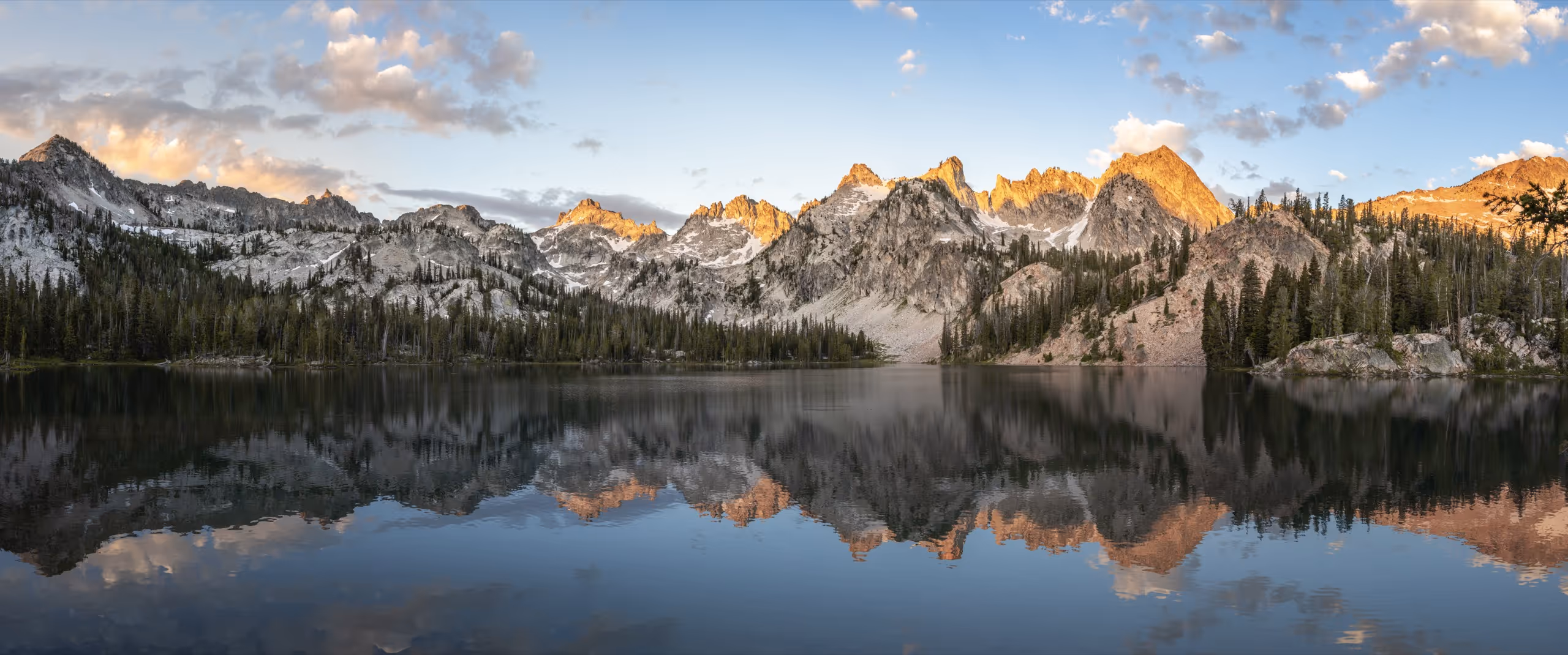 A still alpine lake mirroring the Sawtooth peaks at sunrise.
