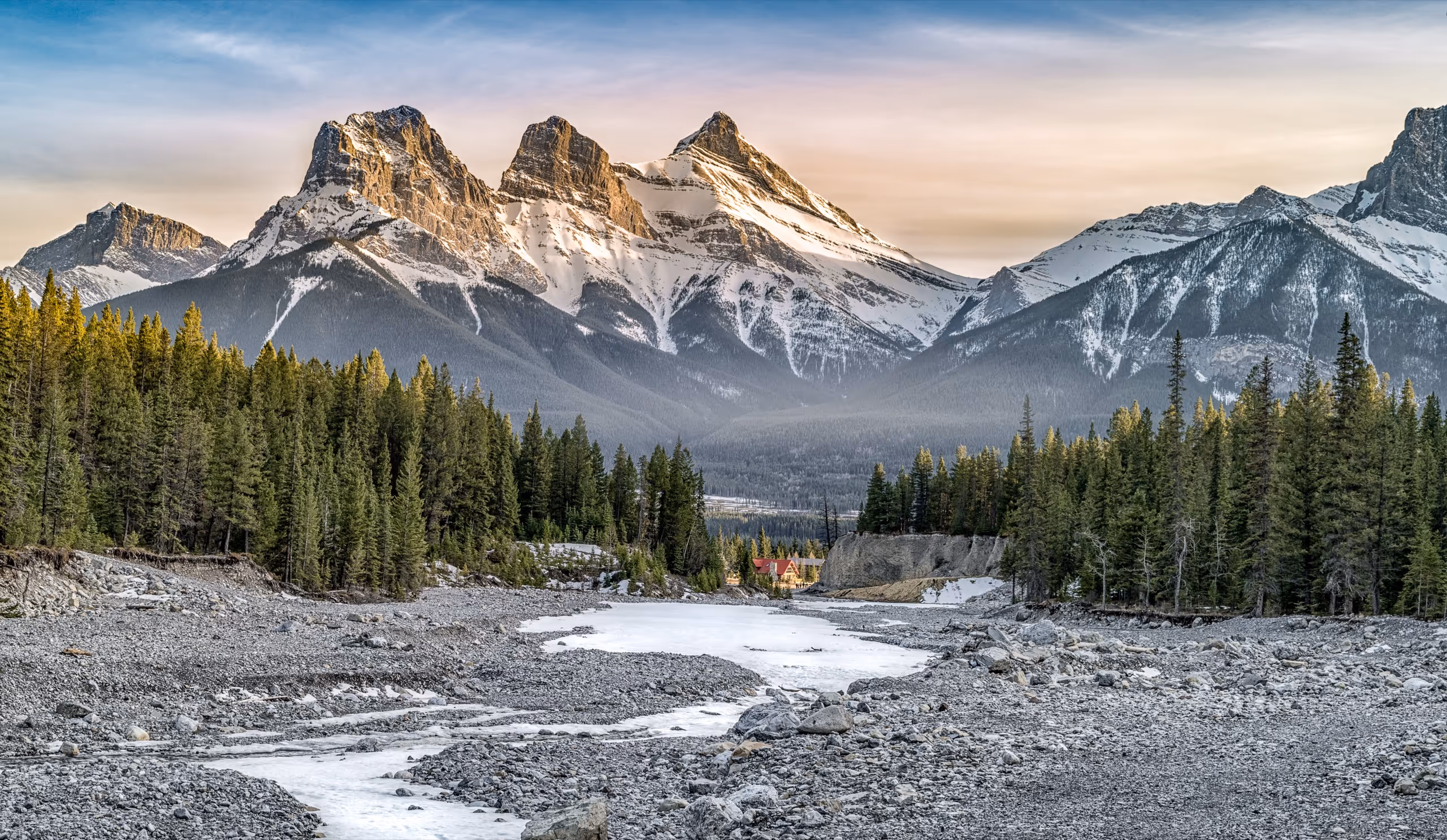 Snow-dusted mountain peaks catching golden light above a forested river valley in Amelia County, Idaho.